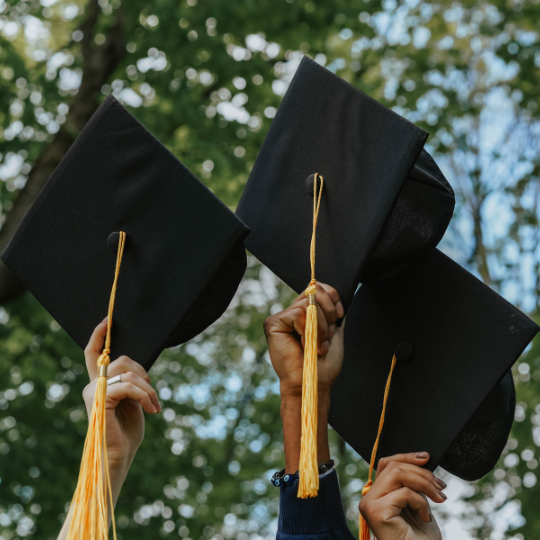 Graduation caps being held up in the air.